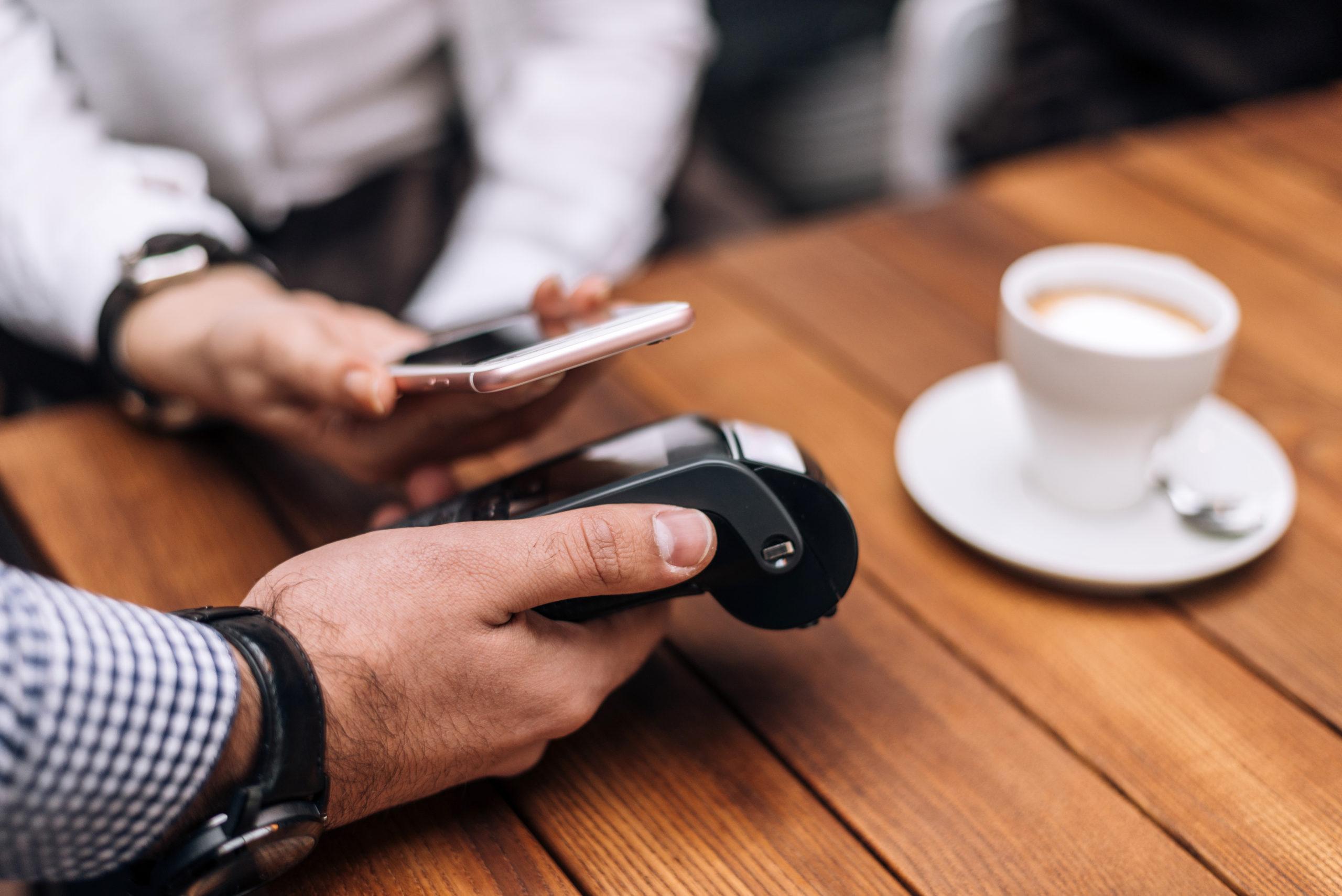 Woman paying for coffee by mobile phone in restaurant.